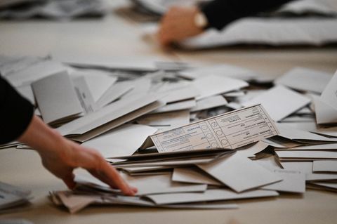 Viele Stimmzettel liegen in einem Wahllokal bei einer Neuwahl