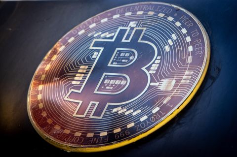 Eine Münze mit Bitcoin-Logo liegt auf schwarzem Untergrund