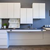 Die barrierefreie Küche  Wer seine Küche rollstuhlgerecht umgestalten möchte, kommt um Sonderlösungen nicht herum. Es gibt mittlerweile optisch attraktive Küchensysteme, deren Design nicht nach Krankenhaus aussieht. Der auf barrierefreie Küchen spezialisierte Hersteller Ropox bietet elektrisch höhenverstellbare Arbeitsplatten einschließlich Spülbecken, die sich mit dem Rollstuhl unterfahren lassen. Auch die ansonsten im Sitzen unerreichbare Hochschränke lassen sich elektrisch absenken. Das System ist auch praktisch, wenn man zusammen mit Kindern kochen oder backen möchte. Je nach Ausbaustufe liegen die Kosten zwischen 2000 und 4800 Euro. Einbauen kann es jedes Küchenstudio oder Schreiner.   Bei den Unterschränke gilt: ausfahrbare Schubladen statt Türen. Auf dem Kochfeld sollten die Induktionszonen nebeneinander liegen, damit im Sitzen nicht über heiße Töpfe gegriffen werden muss. Praktisch ist zudem ein flaches Spülbecken mit einer ausziehbaren Verlängerung des Wasserhahns. Der Backofen sollte zur Seite öffnen lassen und auf Höhe der Arbeitsplatte montiert sein.   Für die Gewährung von Fördermitteln über die Pflegestufe oder einen KfW-Kredit muss die DIN-Norm 18040-2 erfüllt werden. Es gibt Handwerksbetriebe, die neben Planung und Durchführung auch die Beantragung von Fördermitteln übernehmen. 