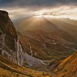 Eine Gipfelkette mit Strahlen der Abendsonne und den Serpentinen des Alpenpasses Colle di Tenda
