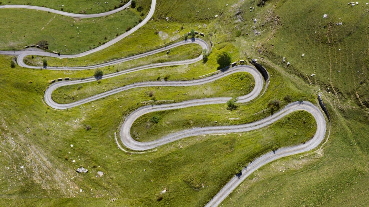 Grüne Wiese mit engen Serpentinen aus der Luft am Alpenpass Colle Valcavera