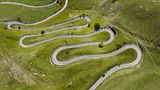 Grüne Wiese mit engen Serpentinen aus der Luft am Alpenpass Colle Valcavera