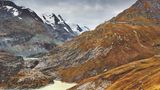 Braune Alpenmatten nahe dem Alpenpass der Großglockner Hochalpenstrasse und im Hintergrund der Großglockner mit Schnee
