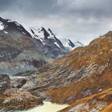 Braune Alpenmatten nahe dem Alpenpass der Großglockner Hochalpenstrasse und im Hintergrund der Großglockner mit Schnee