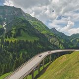 Eine auf Stelzen frei stehende Kehre der Autostraße am Hochtannbergpass mit Bergpanorama