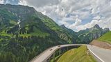 Eine auf Stelzen frei stehende Kehre der Autostraße am Hochtannbergpass mit Bergpanorama