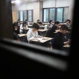 durch ein Fenster sieht man Schüler in einem Klassenraum bei einer Prüfung in Südkorea