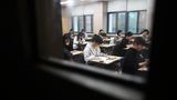 durch ein Fenster sieht man Schüler in einem Klassenraum bei einer Prüfung in Südkorea
