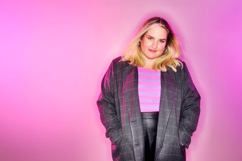 Gulia Becker steht vor einem pinken Hintergrund.