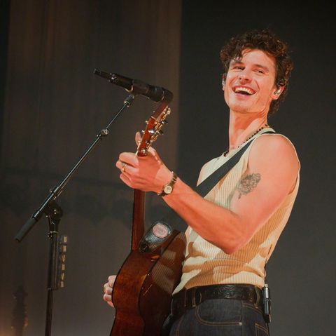 Shawn Mendes lacht in Berlin in die Kamera, während er im Unterhemd Gitarre spielt