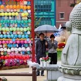 Eltern beten an einem bunt geschmückten buddhistischen Tempel für den Erfolg ihres Kindes