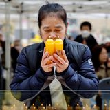 Eine Mutter hält Kerzen in der Hand und betet für den Erfolg ihres Kindes