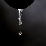 Wasser tropft aus einem tauenden Eiszapfen, der an einer Dachrinne hängt