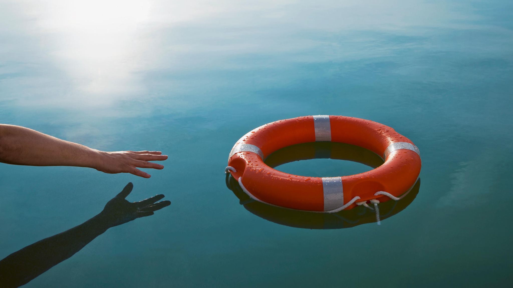 Eine Hand greift nach einem Rettungsring. Ausweg aus der Krise?