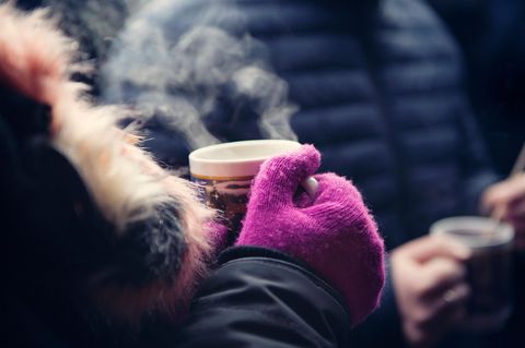 Frau hält einen Becher mit Glühwein auf dem Weihnachtsmarkt