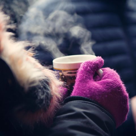 Frau hält einen Becher mit Glühwein auf dem Weihnachtsmarkt