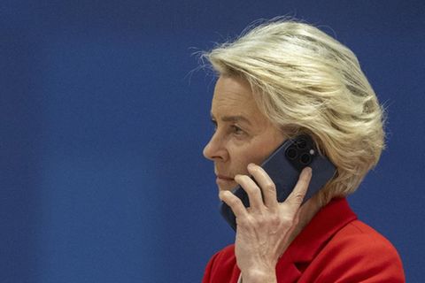 Vor einer blauen Wand mit Aufschrift "European Council" ("Rat der EU") steht Ursula von der Leyen und telefoniert – mit Pfizer?