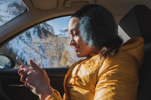 Frau sitzt im Winter im Auto