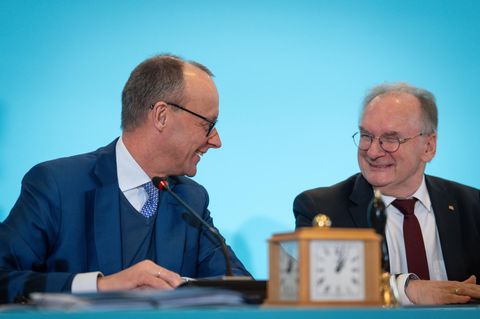 Friedrich Merz und Reiner Haseloff sitzen auf einer Pressekonferenz und lachen.
