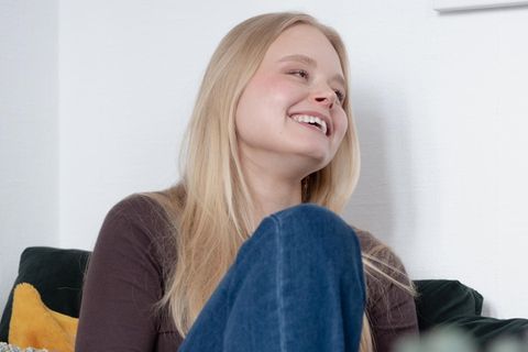 Marie Joan sitzt lächelnd auf einer Couch