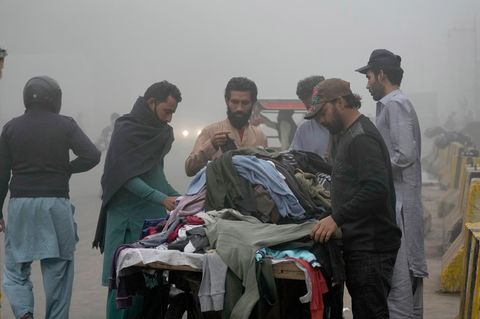 Menschen stöbern in Pakistan an einem Stand nach recycelter Kleidung für den Winter.