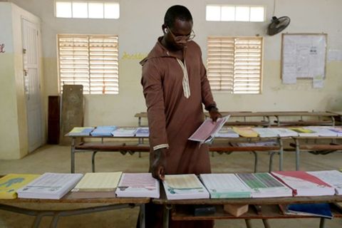 Mann nimmt sich Stimmzettel in Wahllokal in Dakar