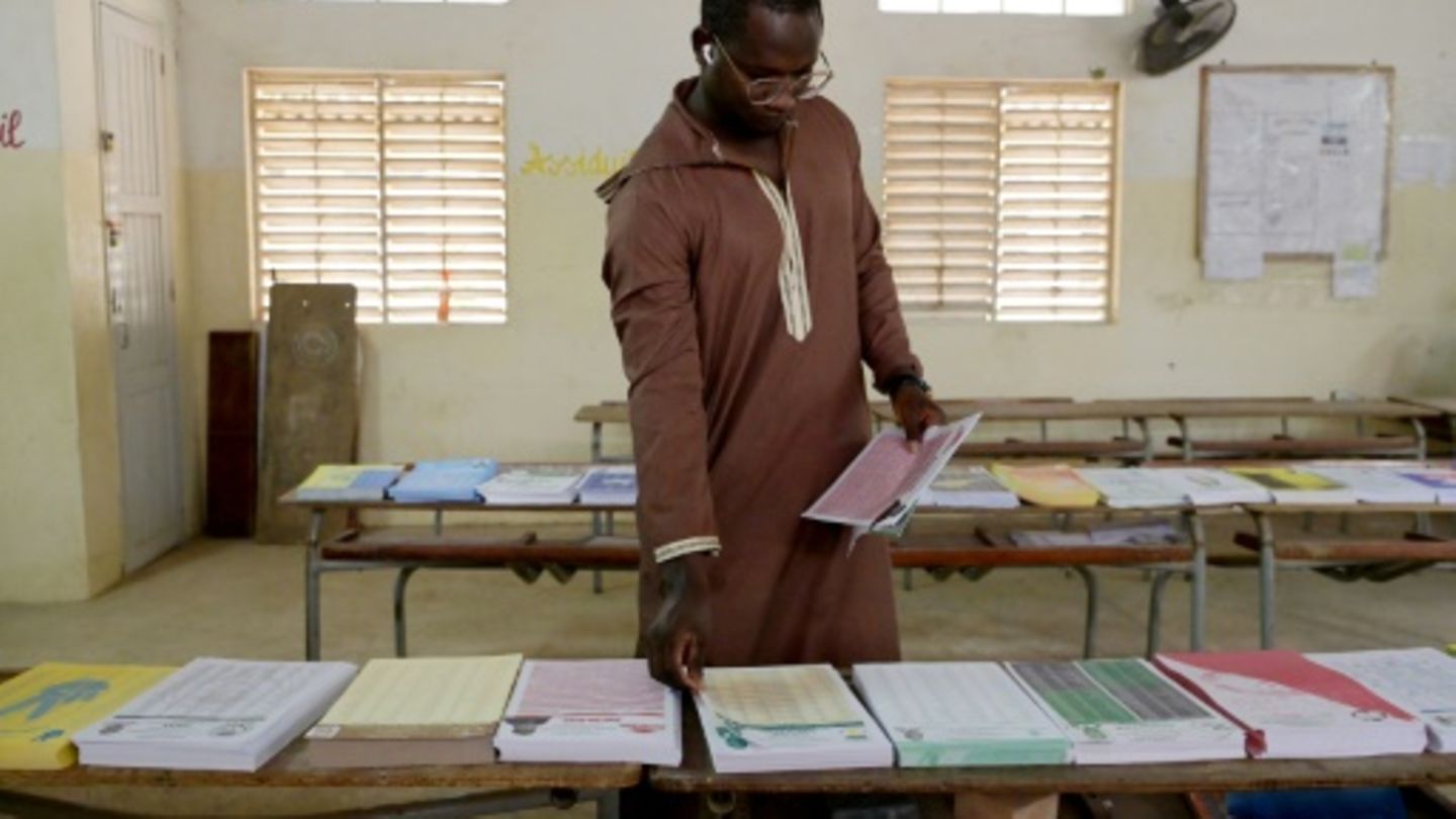 Mann nimmt sich Stimmzettel in Wahllokal in Dakar