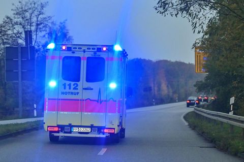 Ein Rettungswagen fährt mit Blaulicht auf einer zweispurigen Straße in Brandenburg