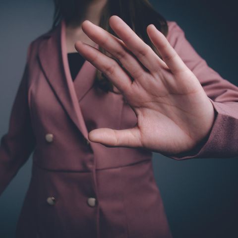 Gewalt gegen Frauen: Eine Frau im Blazer hält eine Hand in die Kamera