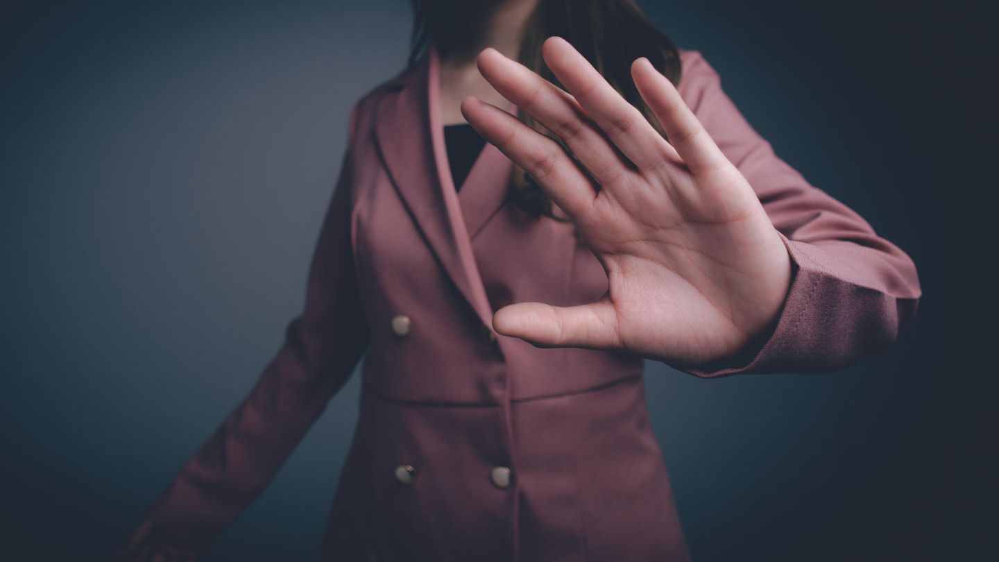 Gewalt gegen Frauen: Eine Frau im Blazer hält eine Hand in die Kamera