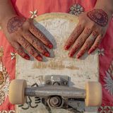 Asha mit traditioneller Henna-Bemalung auf ihren Händen, während sie ihr Skateboard hält