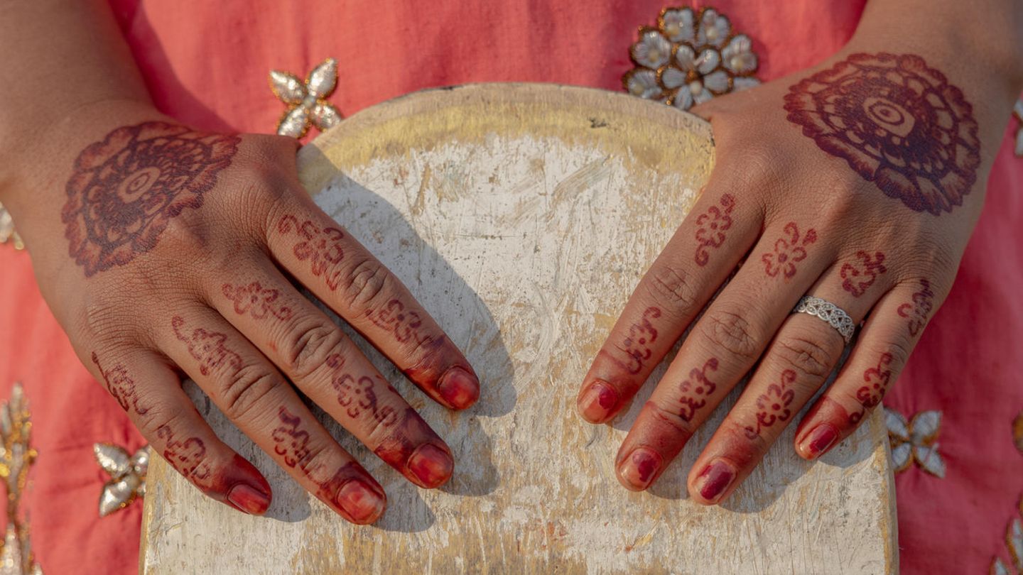 Asha mit traditioneller Henna-Bemalung auf ihren Händen, während sie ihr Skateboard hält