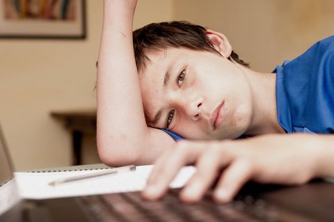 Schüler sitzt alleine lustlos bei den Hausaufgaben