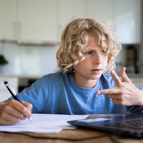 Ein Junge sitzt am Schreibtisch und rechnet mit seiner Hand