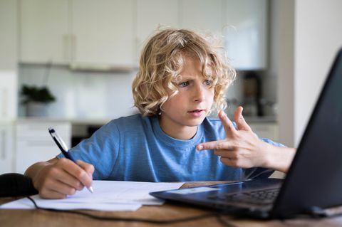 Ein Junge sitzt am Schreibtisch und rechnet mit seiner Hand