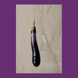 Eine Aubergine und ein Tampon, die an einem Seil in einem Kondom hängen
