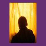 Eine Frau, die mit dem Rücken zum Fenster steht, in warmen Gegenlicht