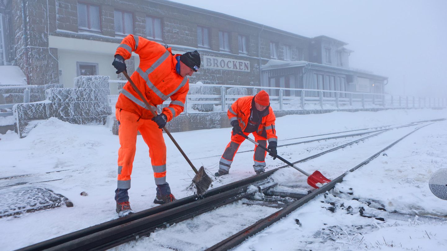 Mitarbeiter der Harzer Schmalspurbahnen GmbH schaufeln Schnee aus den Weichen des Brockenbahnhofes.