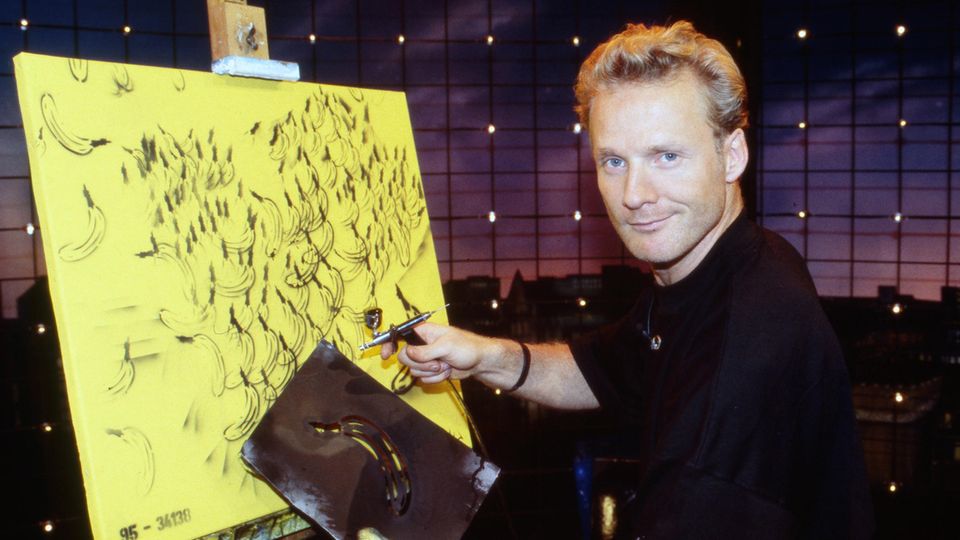 Ein Mann an einer Leinwand stehend mit einer Bananenschablone in der Hand