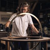 Für eine Globus-Halterung passt ein Mann mit langen Haaren einen Messingring in einen Sockel ein