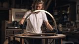 Für eine Globus-Halterung passt ein Mann mit langen Haaren einen Messingring in einen Sockel ein