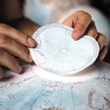 Zwei Hände kleben die Papierscheibe mit dem Nordpol oben auf einen Globus