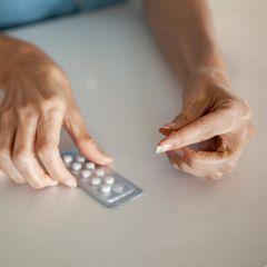 Frauenhände, die eine Tablette (Hormonersatztherapie) aus einer Blisterpackung lösen
