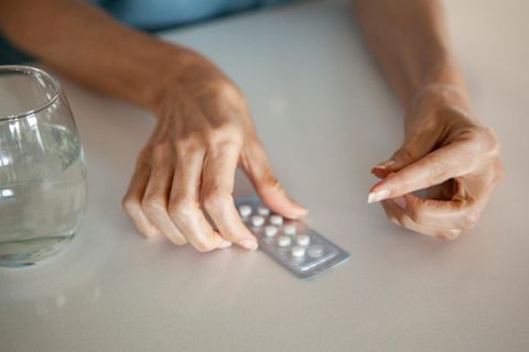 Frauenhände, die eine Tablette (Hormonersatztherapie) aus einer Blisterpackung lösen