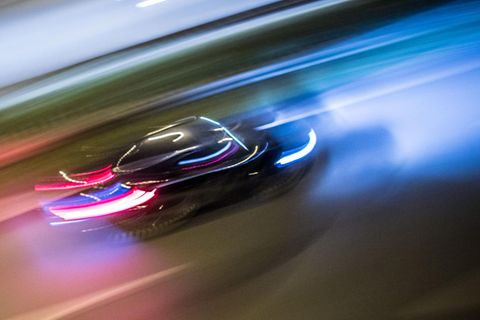 Ein Raser auf der Straße am Abend, leicht verschwommen mit auffallenden Lichtmustern