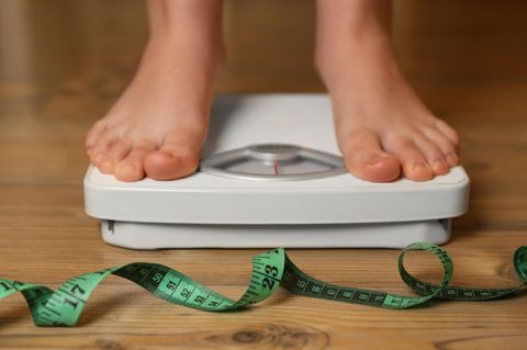Übergewicht Zwei Füße stehen auf eine Waage davor liegt ein Maßband