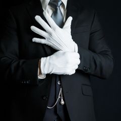 Ein Butler zieht weiße Handschuhe an