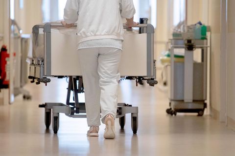 Krankenhausreform: Eine Krankenpflegerin schiebt ein Krankenbett durch einen Krankenhausflur