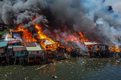 Große hellrote Flammen fressen sich durch die Hütten