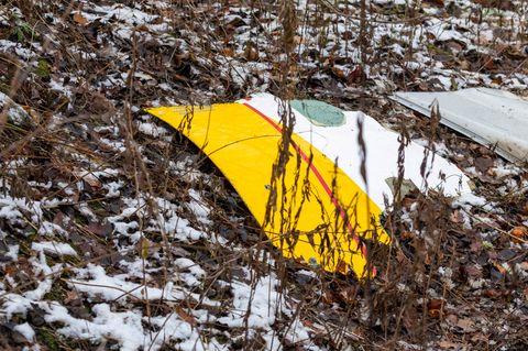 Ein zum Teil DHL-gelb lackiertes Trümmerteil liegt an der Absturzstelle